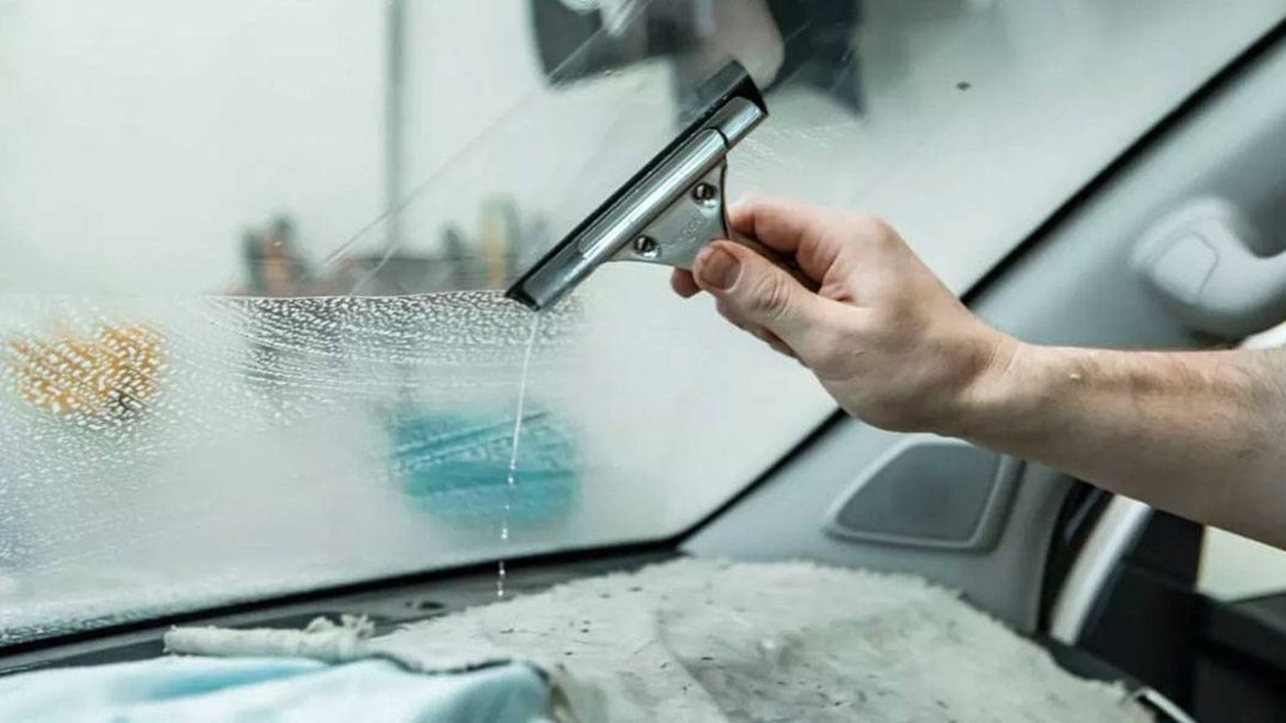 Водій прибирає конденсат із запотілого лобового скла автомобіля